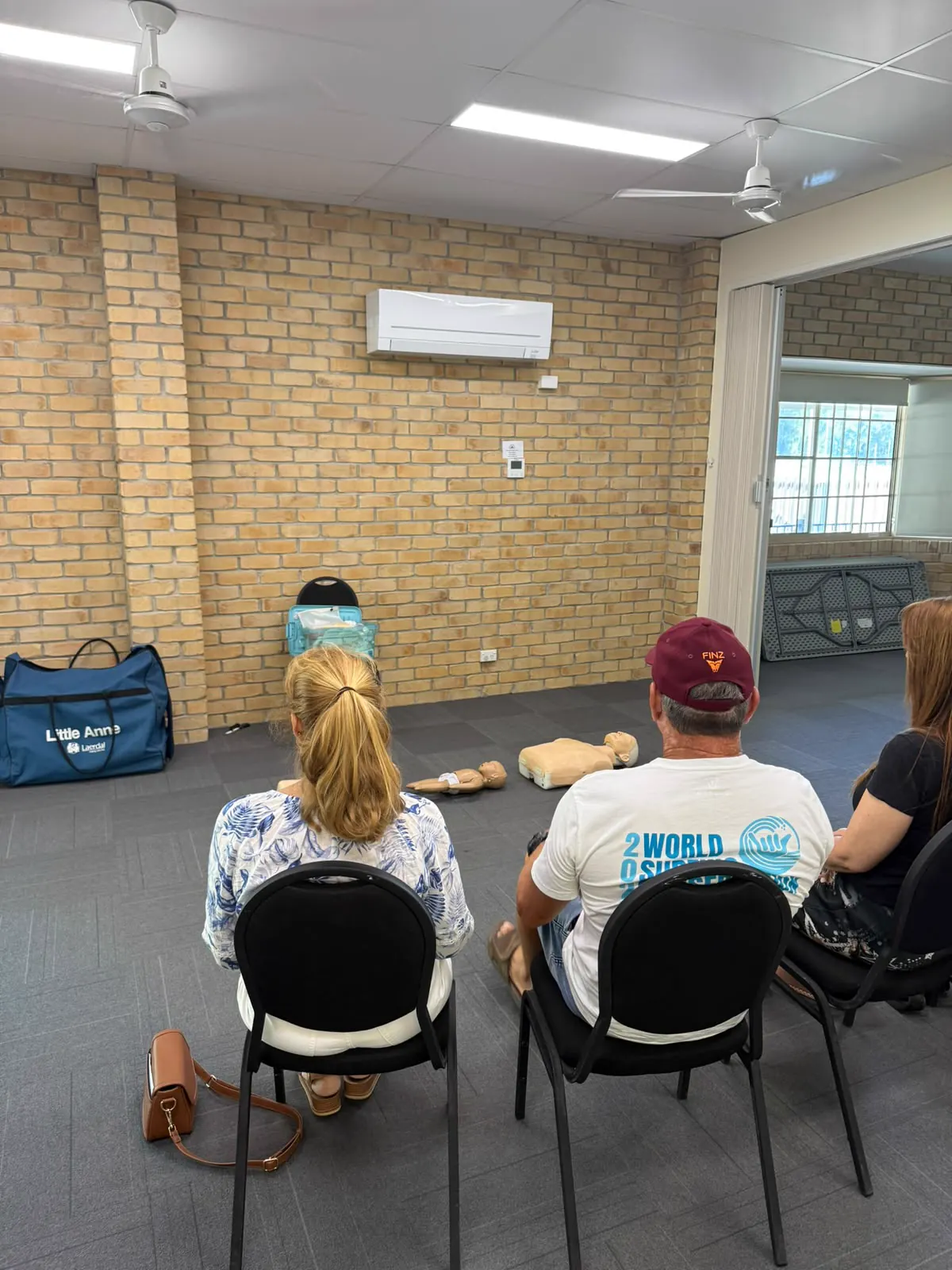 Participants attending an onsite first aid training briefing with manikins ready